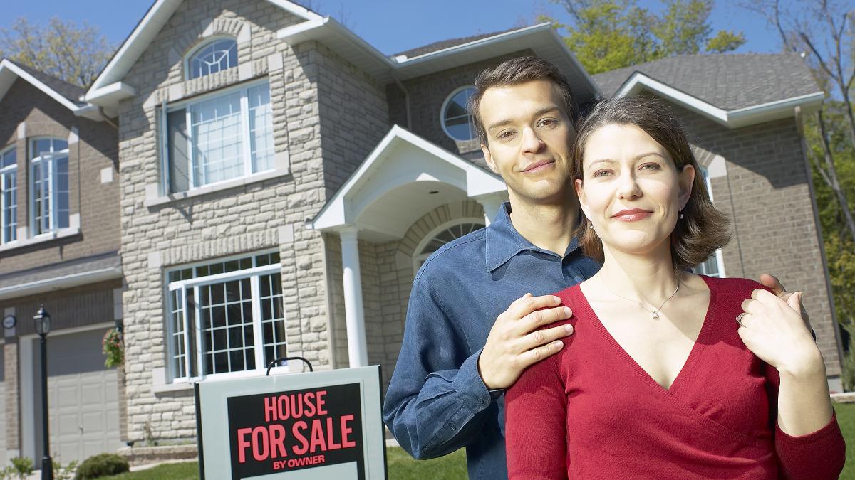 A man and woman standing in front of a house